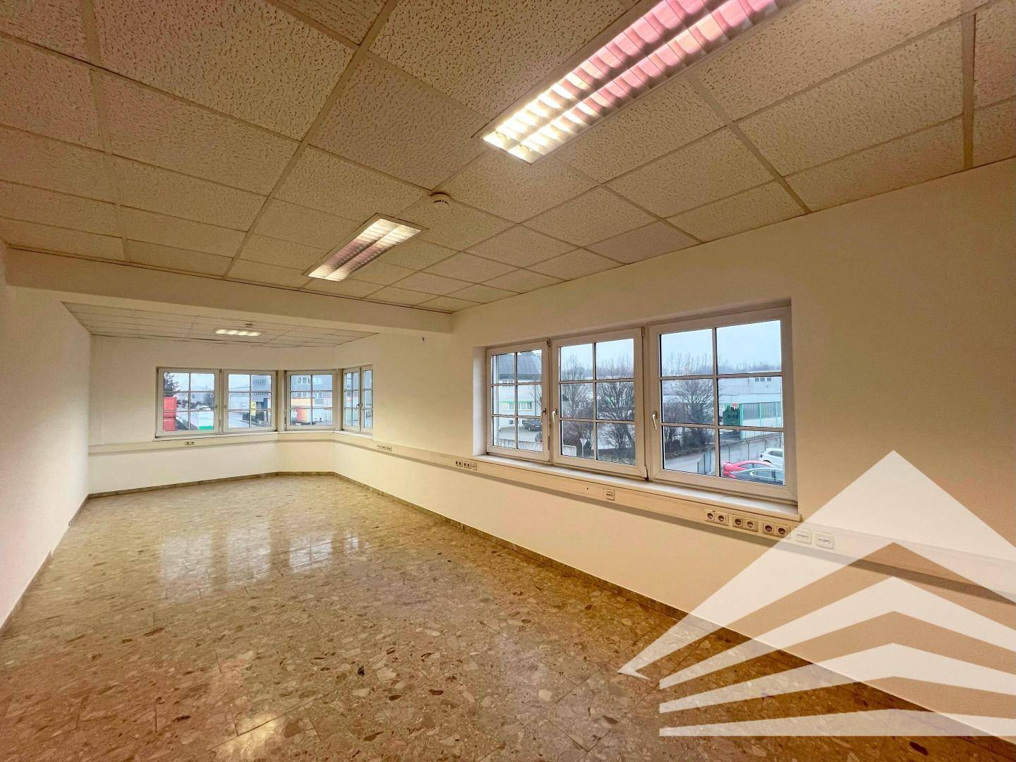 Großes Eckbüro mit vielen Fenstern und einem strapazierfähigen Fliesenboden, ideal für Arbeitsplätze.