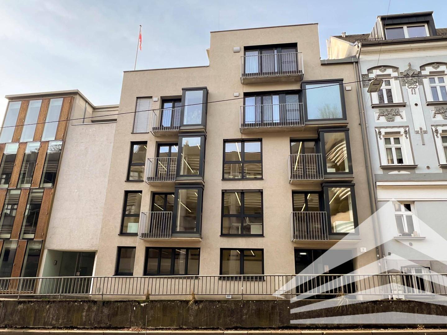 Moderne Gebäudefassade mit vielen Fenstern, Balkonen und einer zeitgenössischen Architektur in städtischer Umgebung.