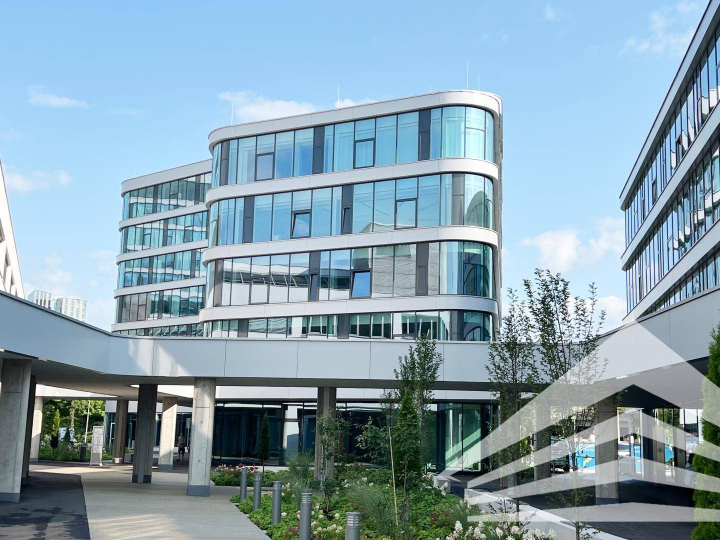 Ansicht eines modernen Bürokomplexes mit markanter Glasfassade und geschwungenen Linien.