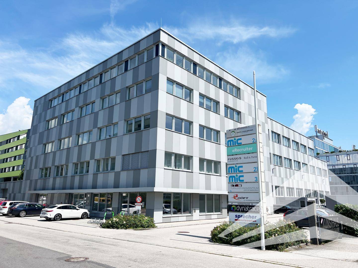 Außenansicht eines modernen Bürogebäudes mit gestreifter Fassade und Firmenschildern.