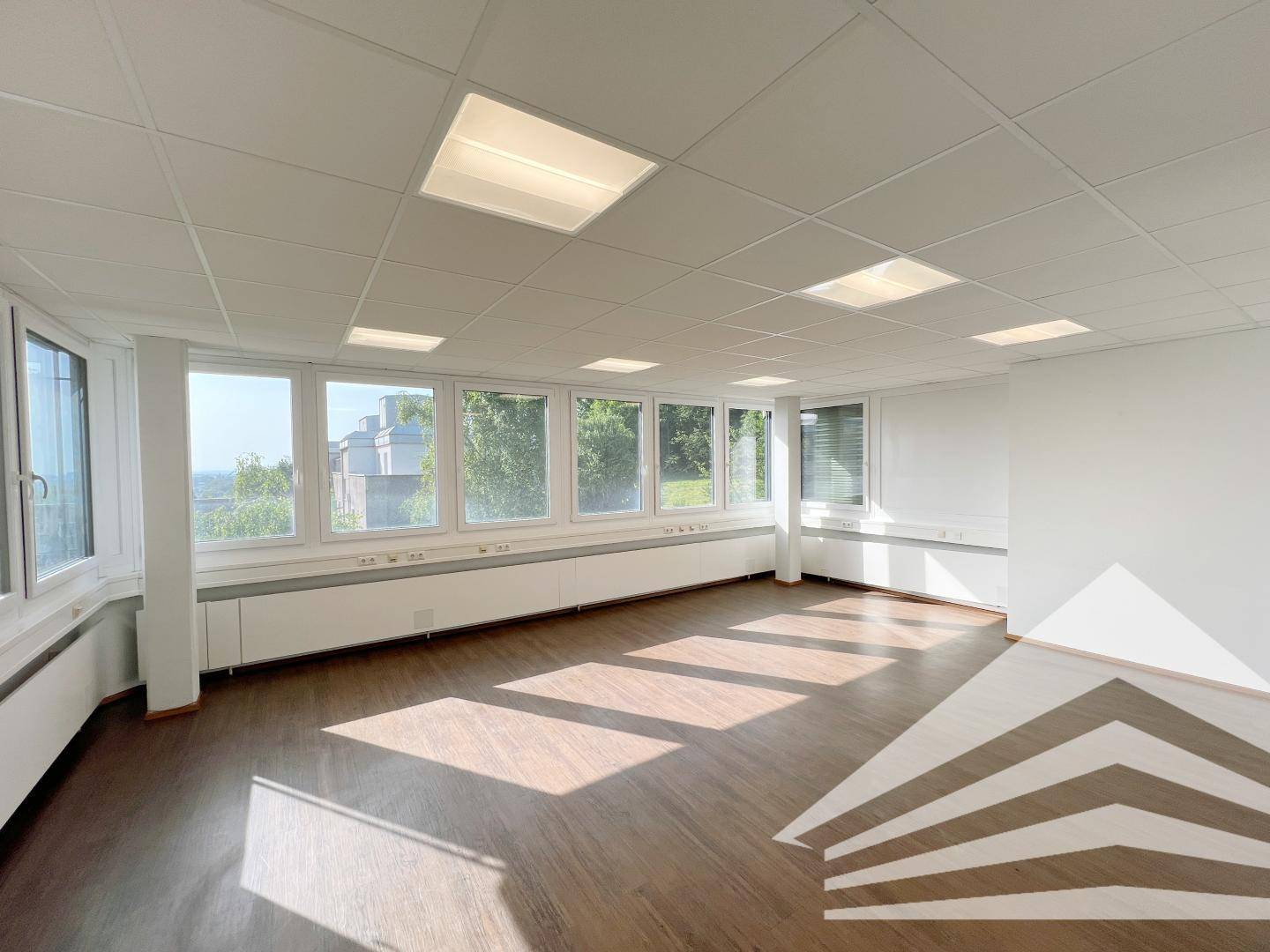 Sonniges Büro mit großen Fenstern, die viel natürliches Licht hereinlassen und einen weiten Blick bieten.