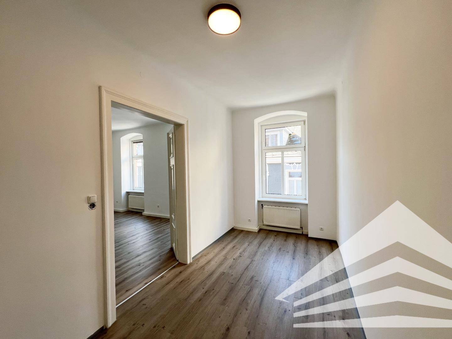 Heller Flur mit Laminatboden und einem Fenster, das den Raum mit natürlichem Licht versorgt.
