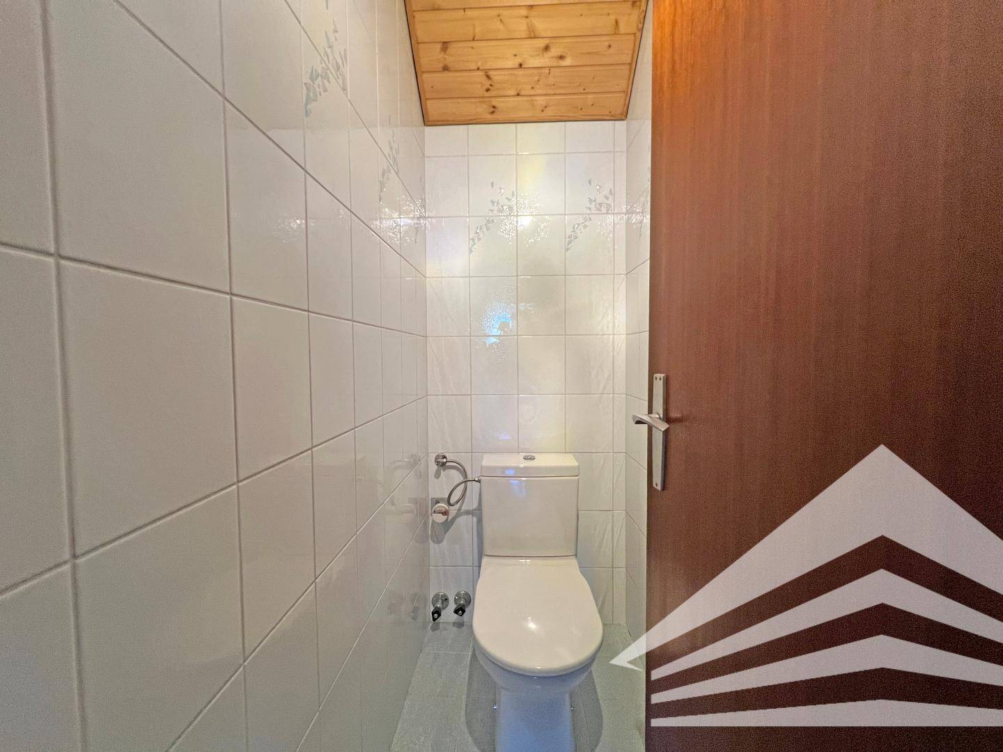 Separates WC mit Toilette und vollständig gefliesten Wänden.