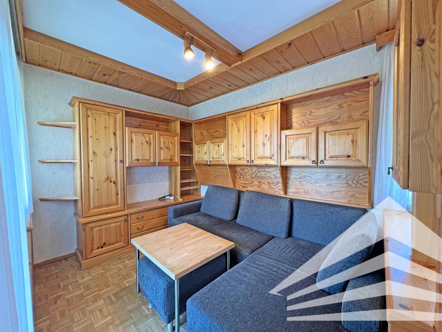 Wohnzimmer mit bequemer Couch, Holzvertäfelung und rustikaler Holzdecke.