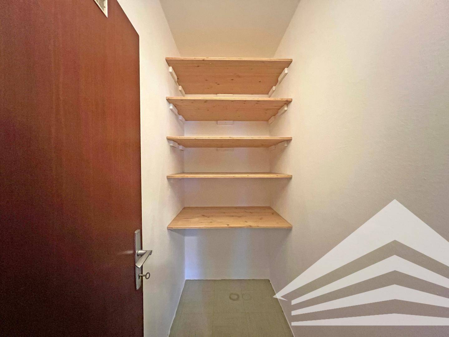 Praktischer Abstellraum mit mehreren Holzregalen für zusätzlichen Stauraum.