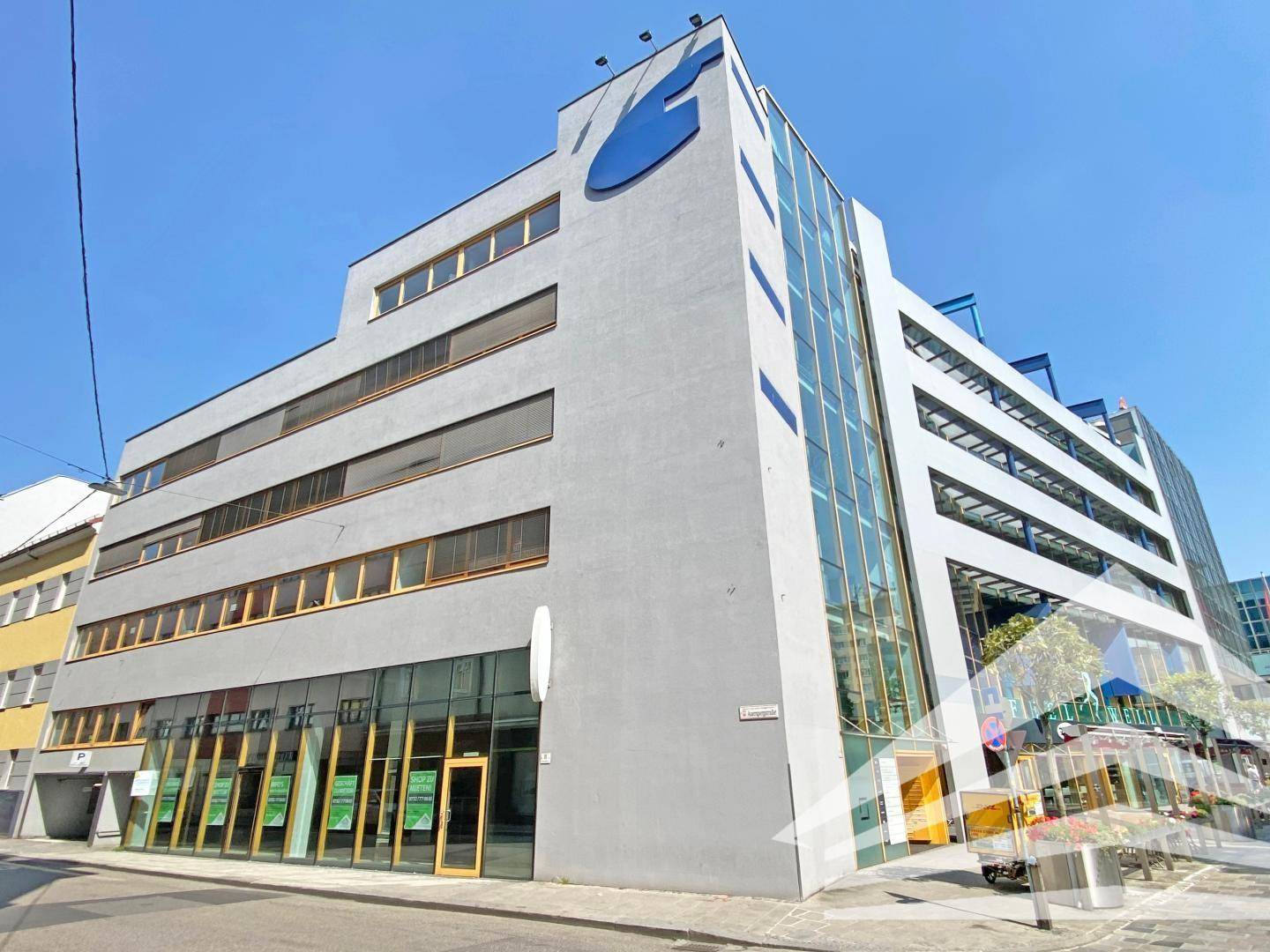 Modernes Geschäftsgebäude mit Glasfassade und mehreren Etagen in städtischer Umgebung.