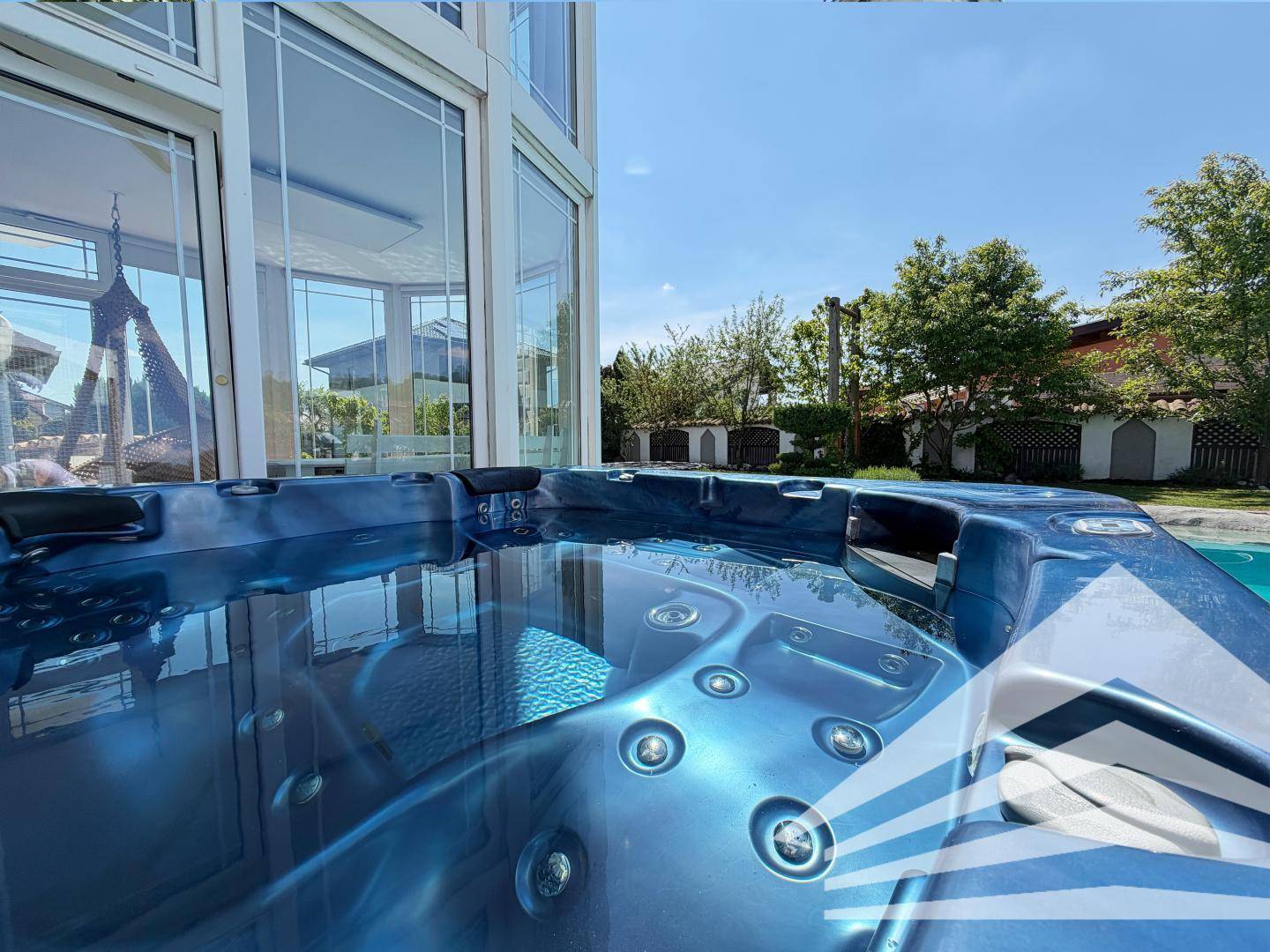 Nahaufnahme des blauen Whirlpools mit sprudelndem Wasser, angrenzend an den Wintergarten.
