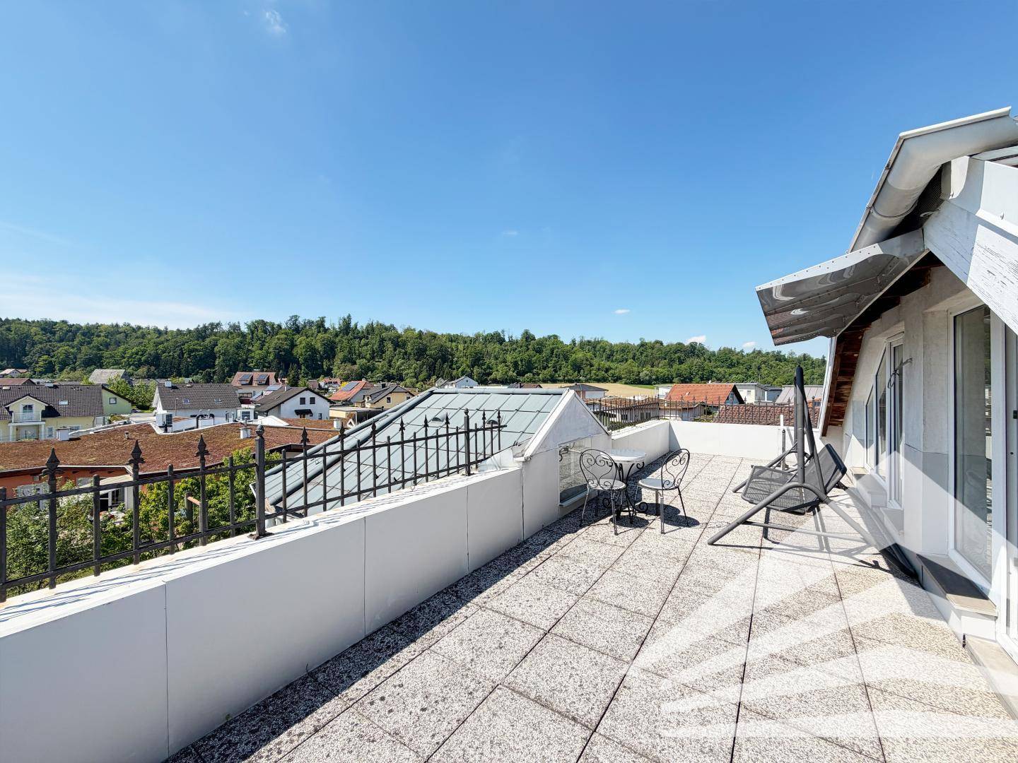 Weitläufige Dachterrasse mit Sitzgelegenheiten und Panoramablick über die Nachbarschaft und grüne Hügel.