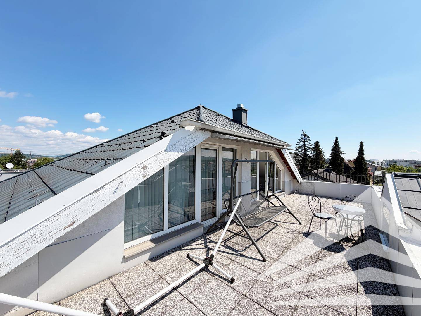 Sonnige Dachterrasse mit Blick auf die Dächer der Umgebung und die weite Landschaft.