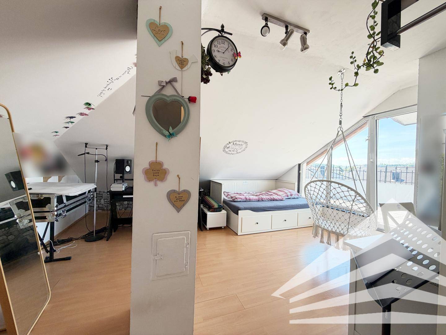 Gemütliches Dachzimmer mit schrägen Decken, Bett, Hängesessel und liebevoller Dekoration.