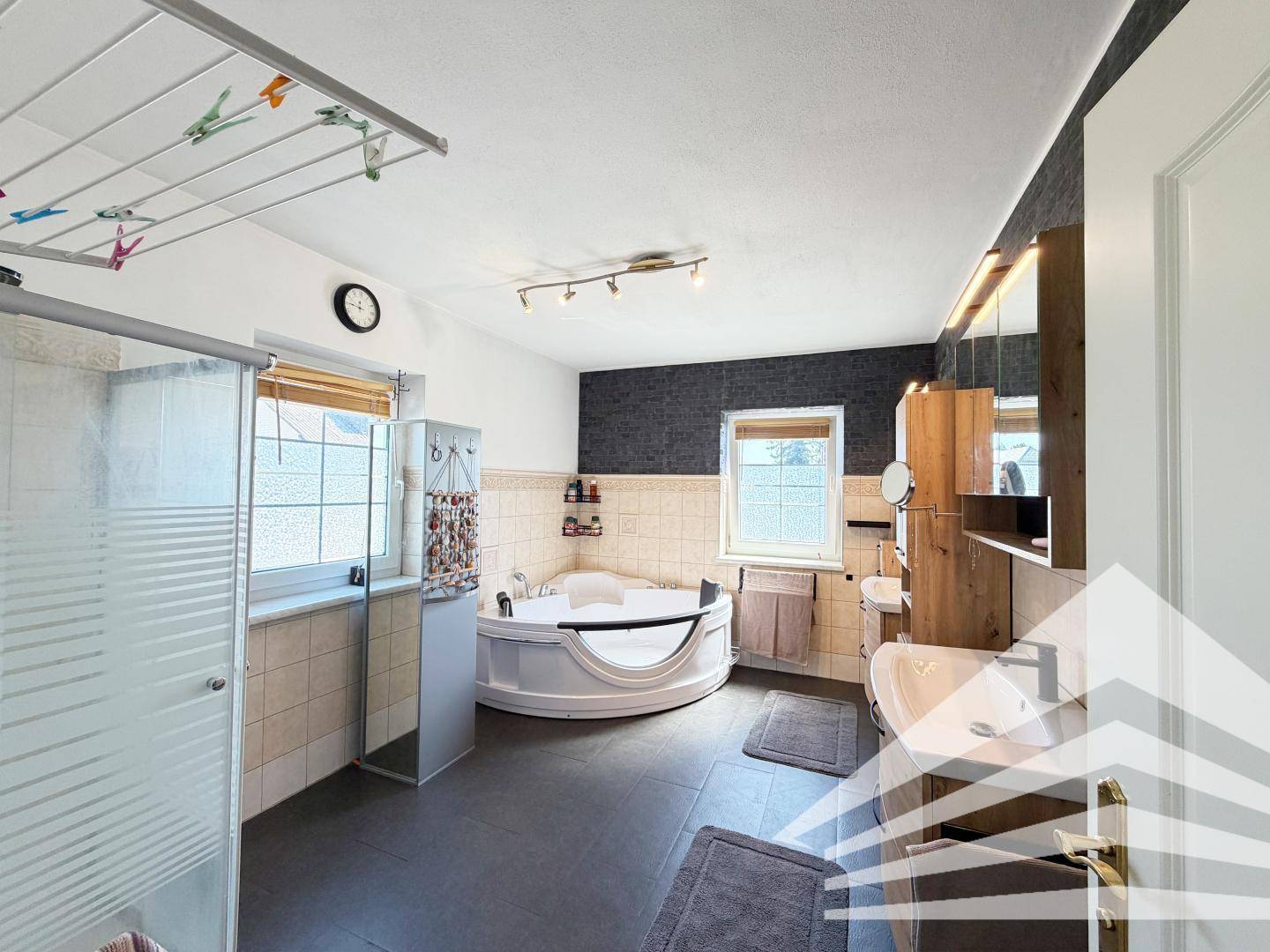 Geräumiges Badezimmer mit Eck-Whirlpool, Duschkabine, Doppelwaschbecken und Fliesen.