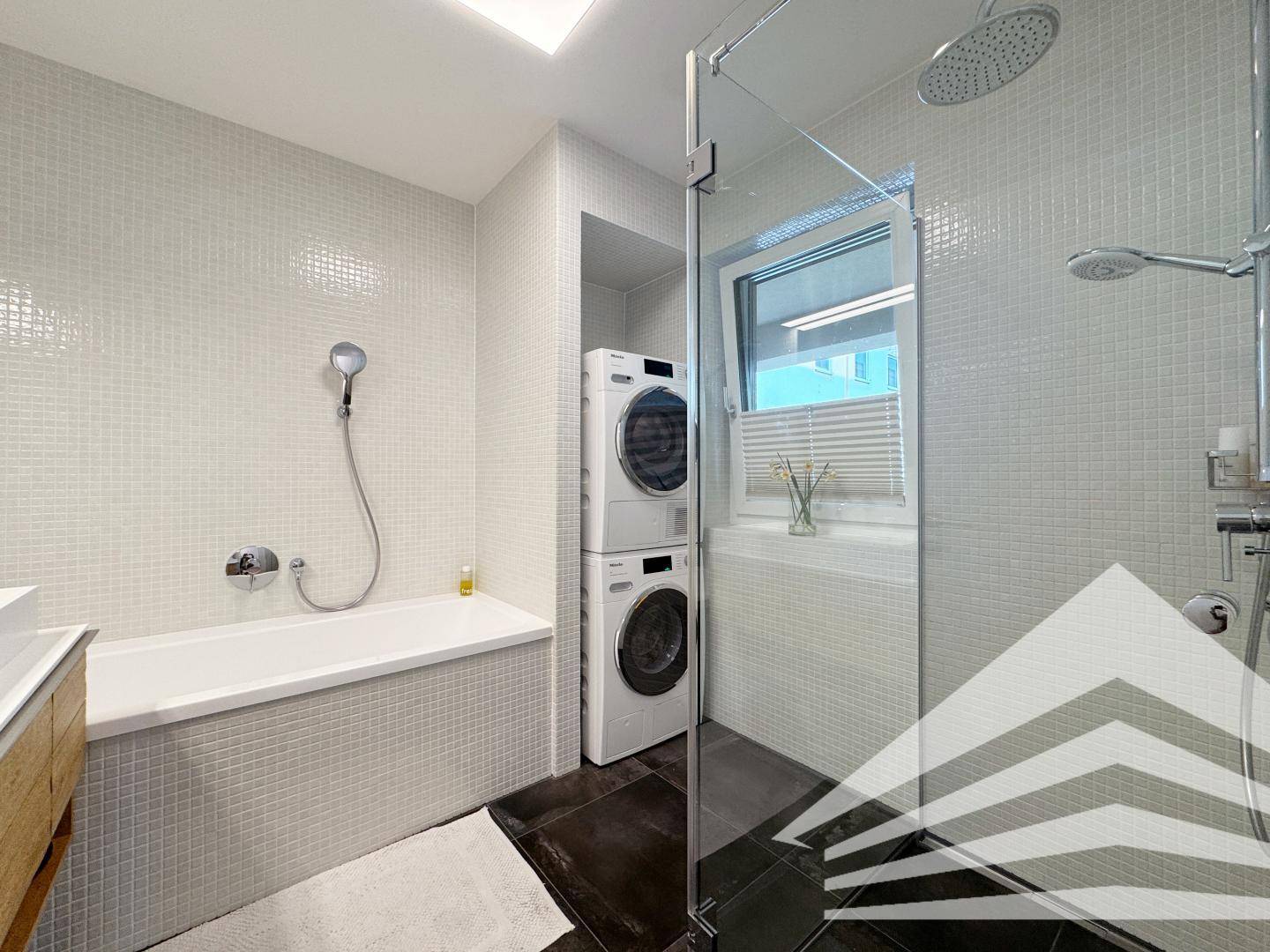 Modernes Badezimmer mit Badewanne, Duschkabine und Waschmaschine/Trockner-Turm.
