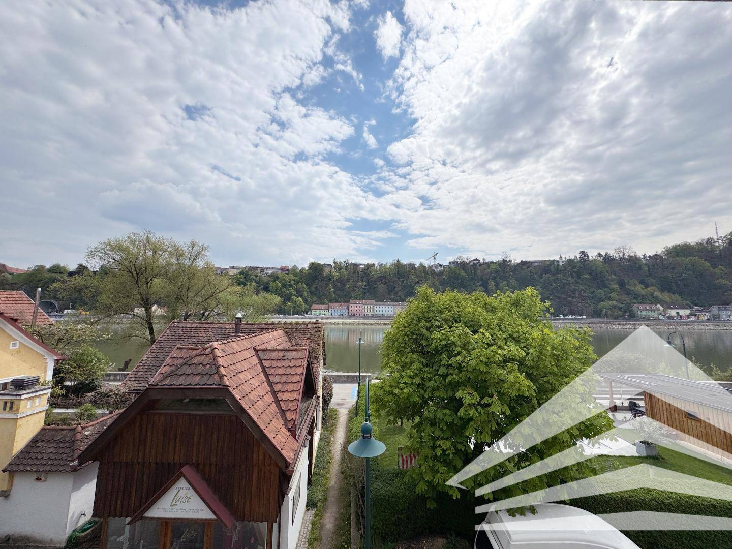 Weitläufiger Blick über den Fluss und die umliegende Landschaft unter einem bewölkten Himmel.