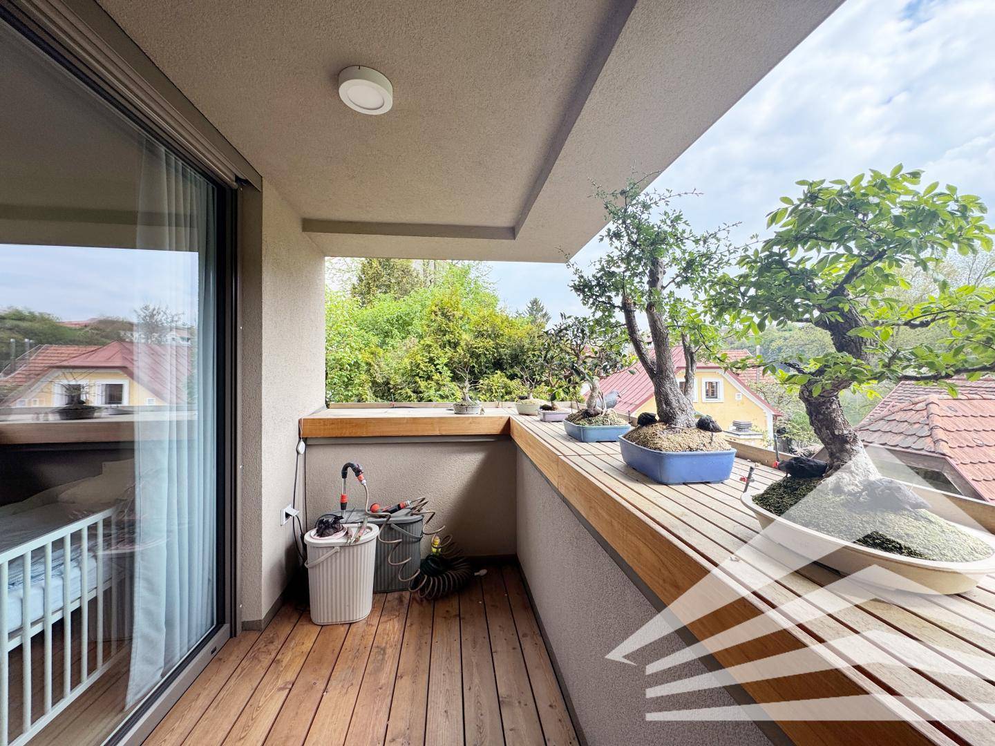 Balkon mit Holzboden und Bonsai-Pflanzen, bietet einen ruhigen Außenbereich.