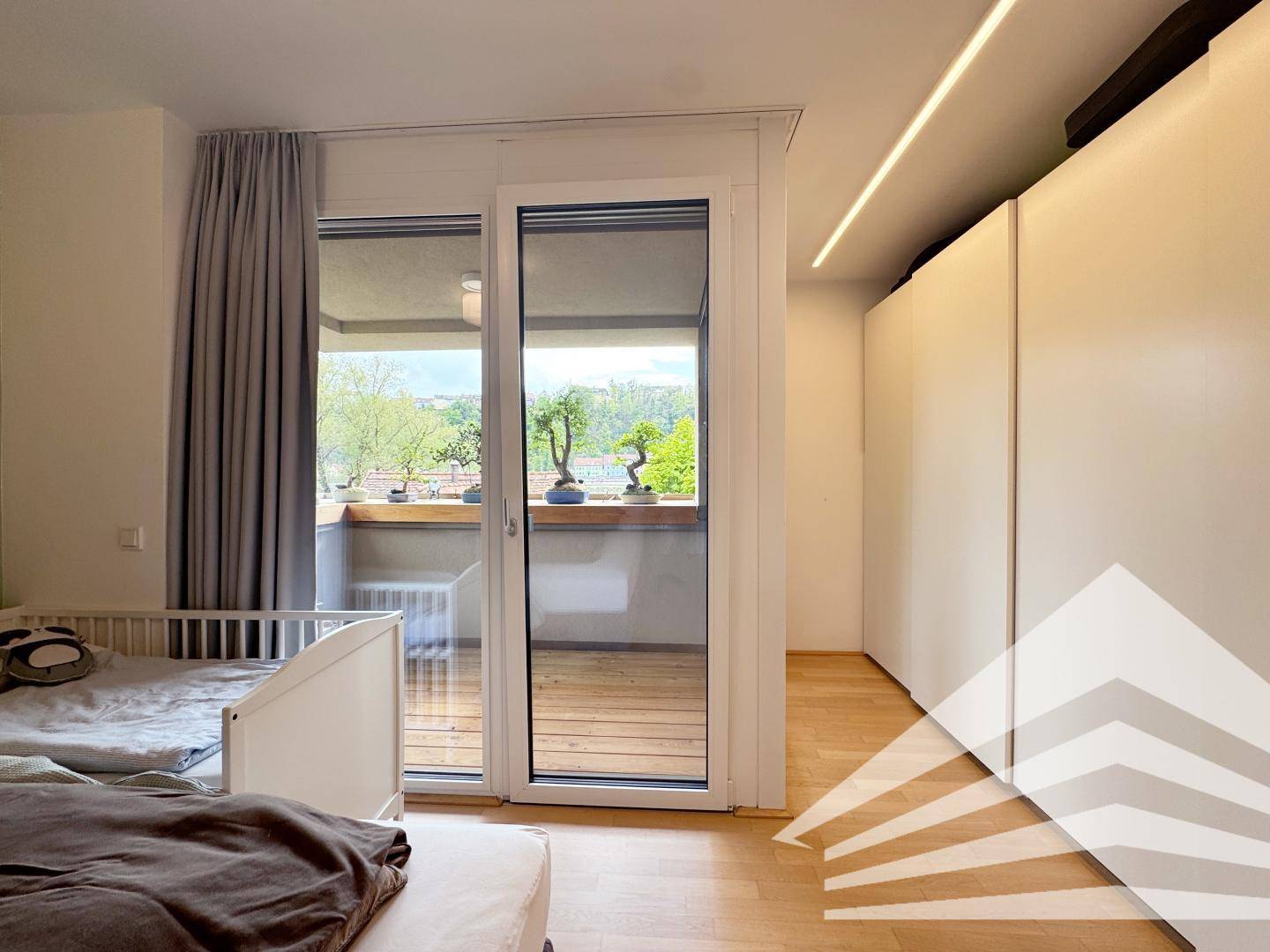 Schlafzimmer mit Zugang zum Balkon, Einbauschränken und Holzboden.
