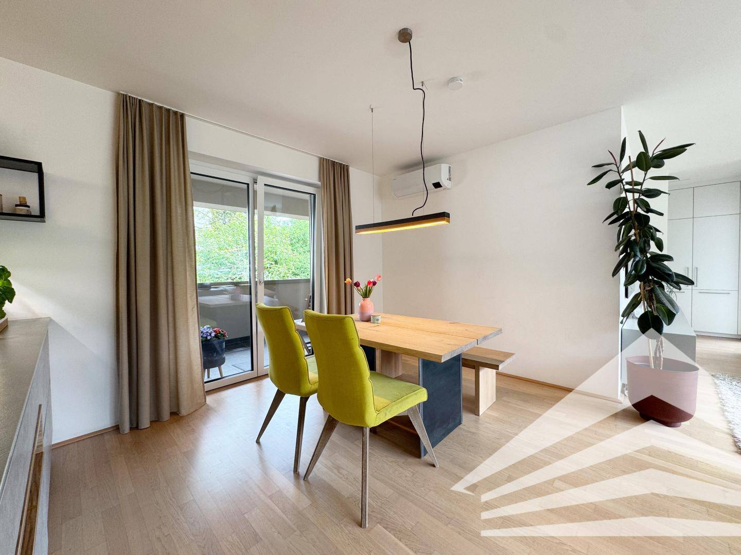 Essbereich mit Holztisch und gelben Stühlen, direktem Zugang zum Balkon und Klimaanlage.