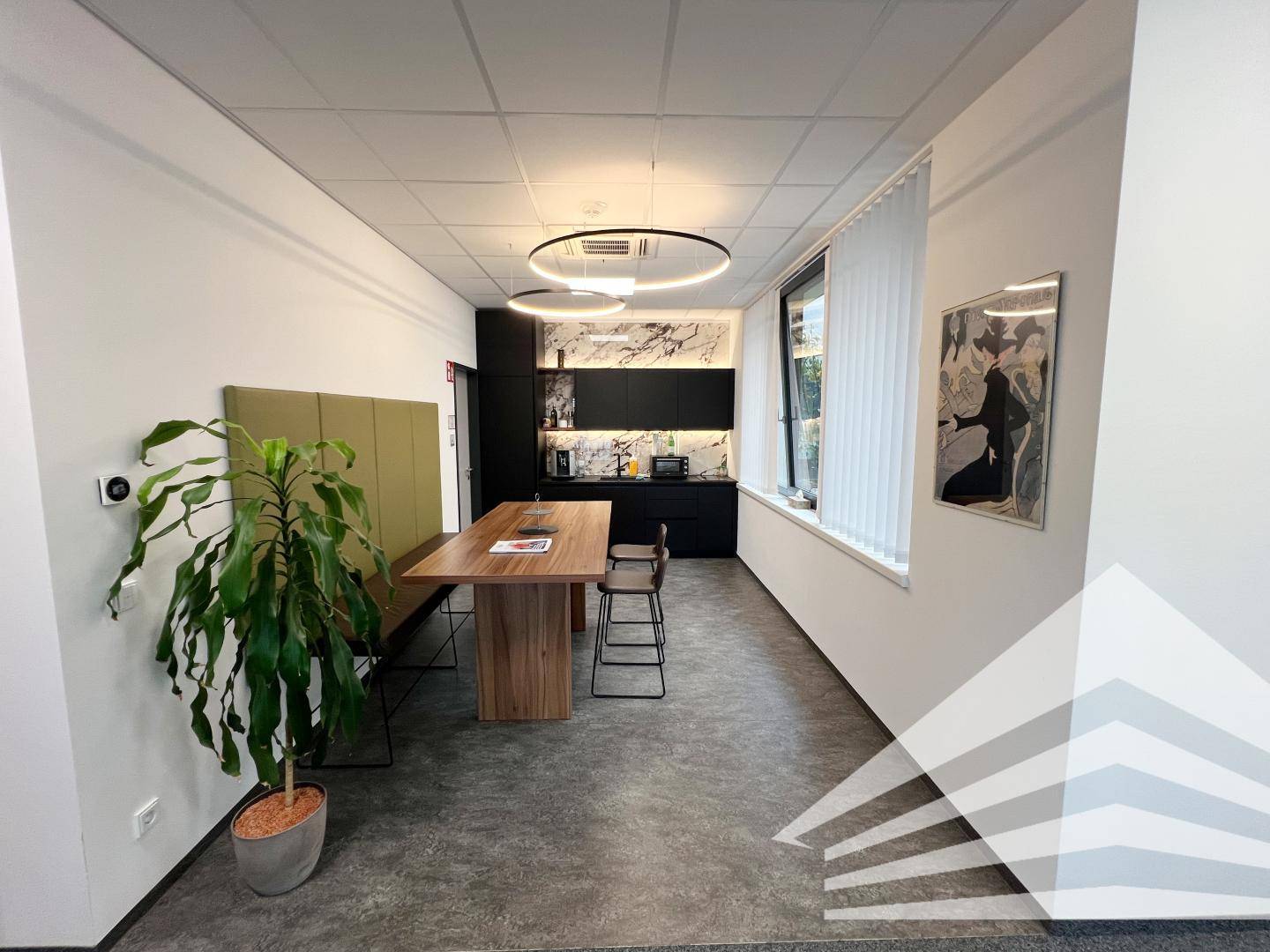 Moderne Teeküche mit Holztisch, Sitzbank und minimalistischer Küchenzeile für Pausen.