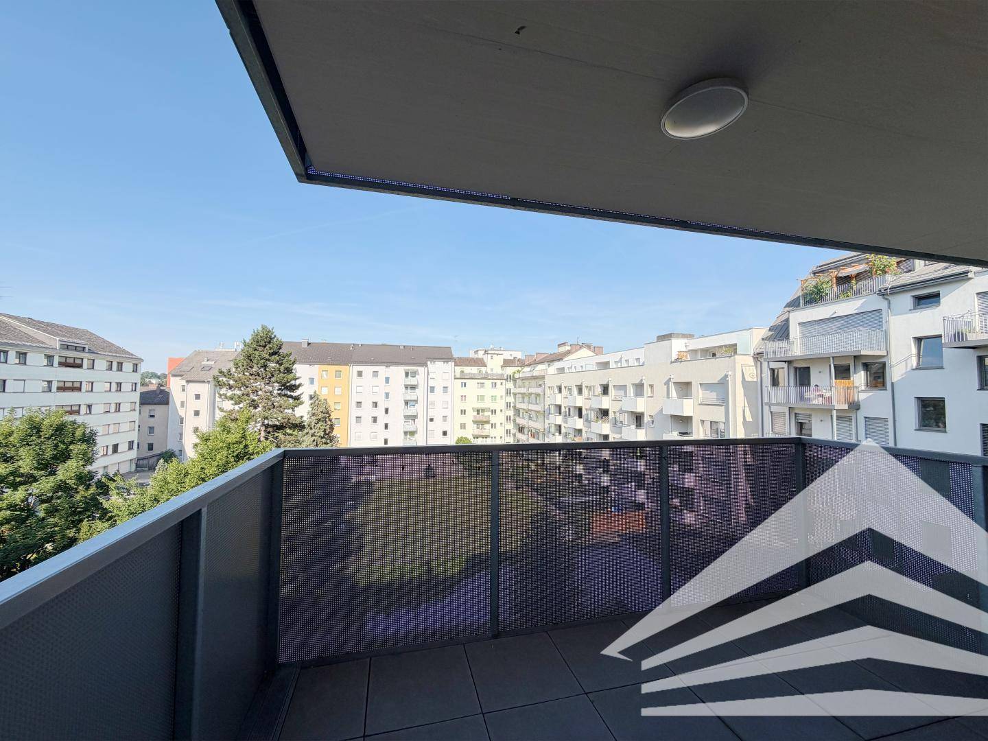 Geräumiger Balkon mit Blick auf die umliegenden Gebäude und viel Grün.