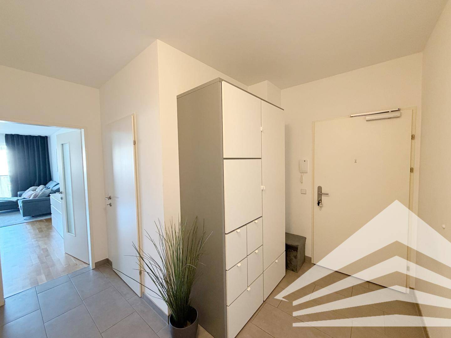 Heller Eingangsbereich mit Fliesenboden und praktischem Einbauschrank für Stauraum.