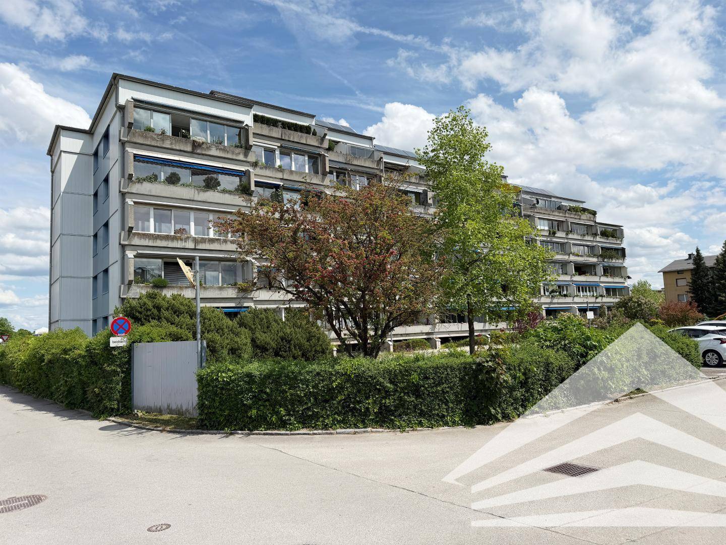 Mehrstöckiges Wohngebäude mit zahlreichen Balkonen und grüner Bepflanzung in der Umgebung.
