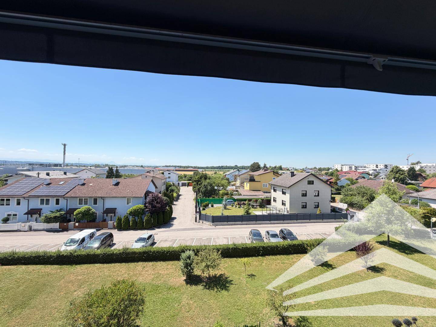 Weitläufiger Blick über die umliegende Wohngegend mit Häusern und Grünflächen unter blauem Himmel.