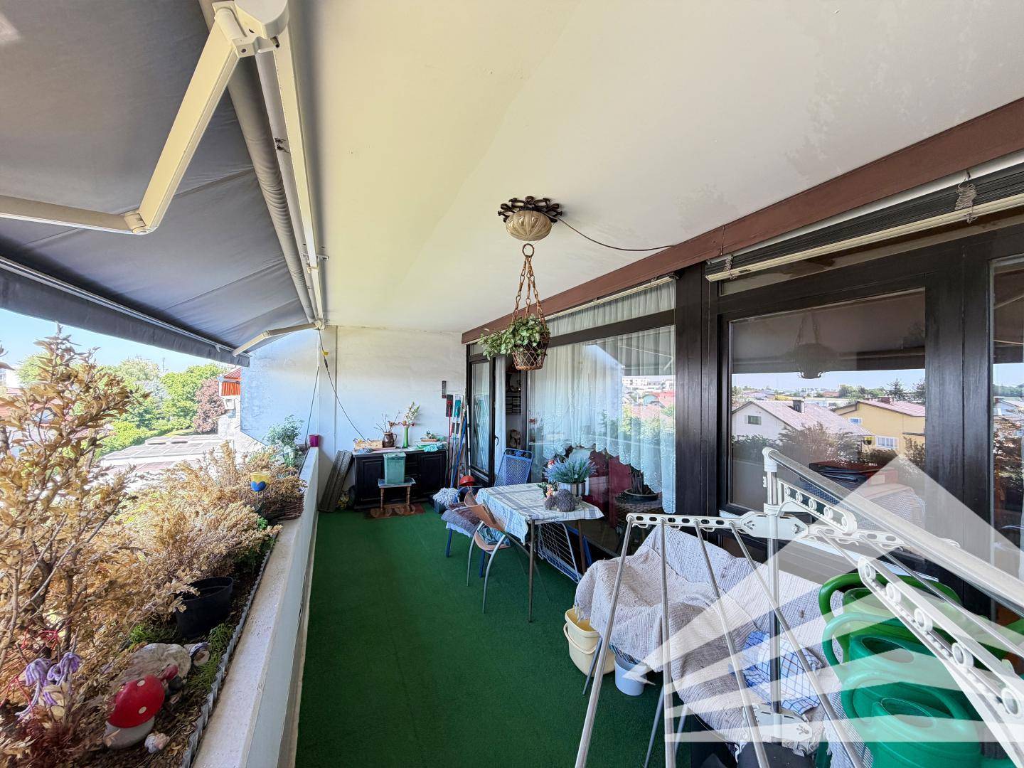 Langer Balkon mit Kunstrasen, Pflanzen und Wäscheständer, bietet zusätzlichen Außenbereich.