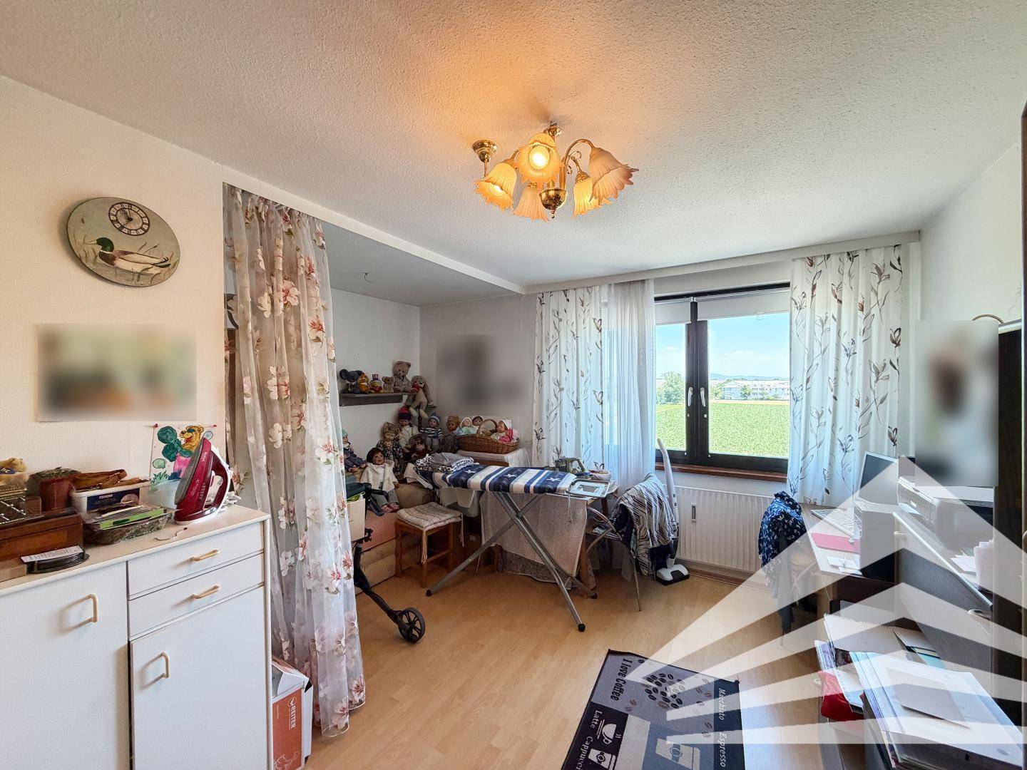 Helles Zimmer mit Fenster, das einen weiten Blick ins Grüne bietet, und einfacher Einrichtung.