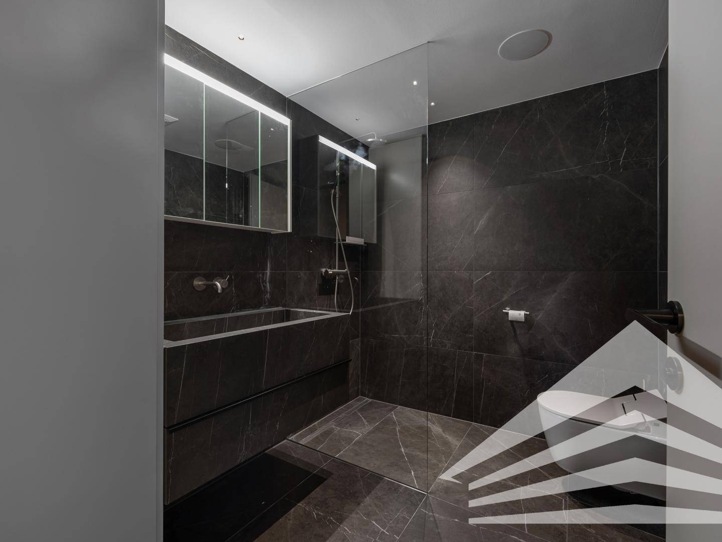 Elegantes Badezimmer in dunklem Marmor-Look mit begehbarer Dusche und modernem Waschtisch.