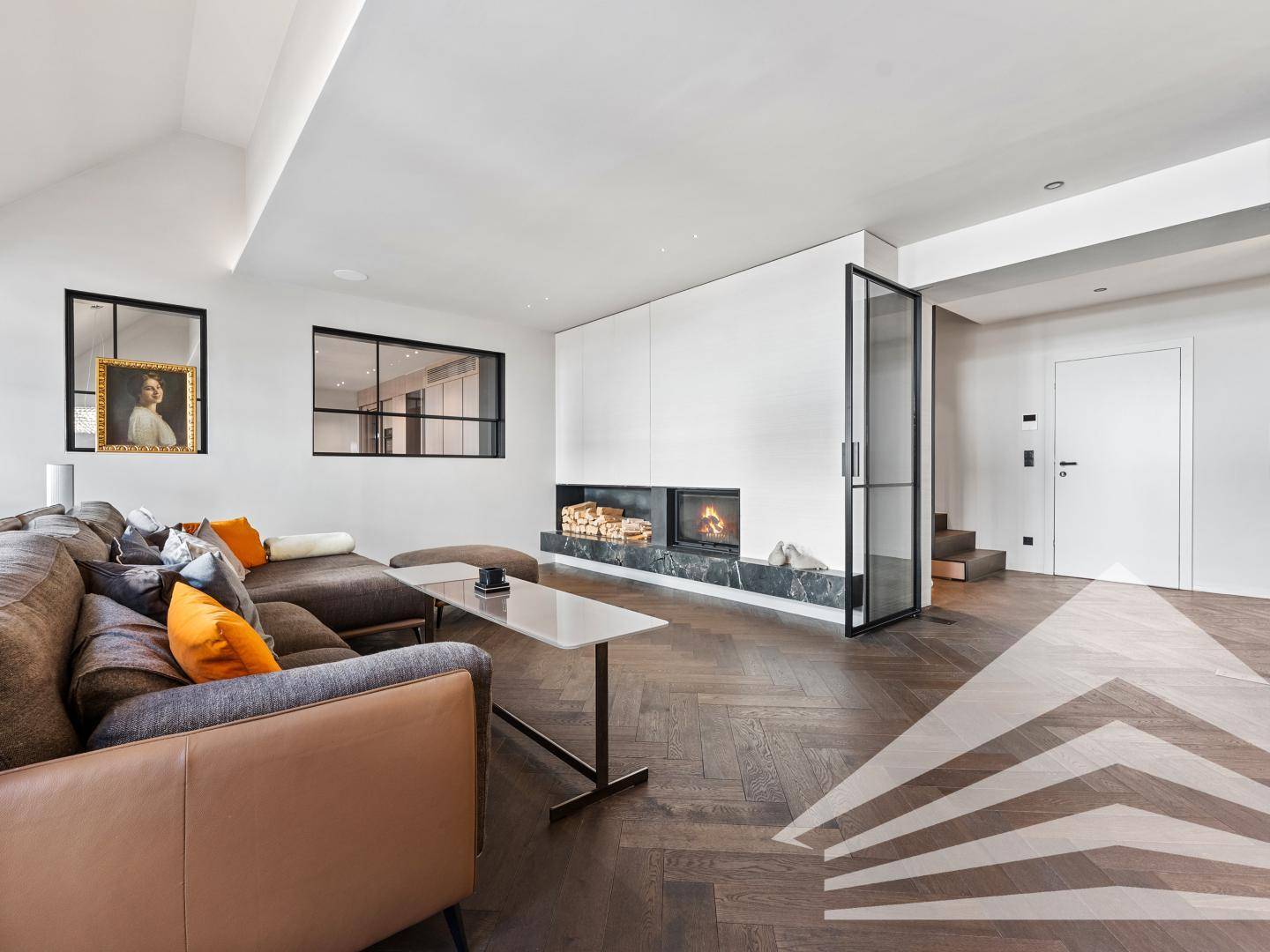 Stilvolles Wohnzimmer mit modernem Kamin, Fischgrätparkett und minimalistischer Einrichtung.
