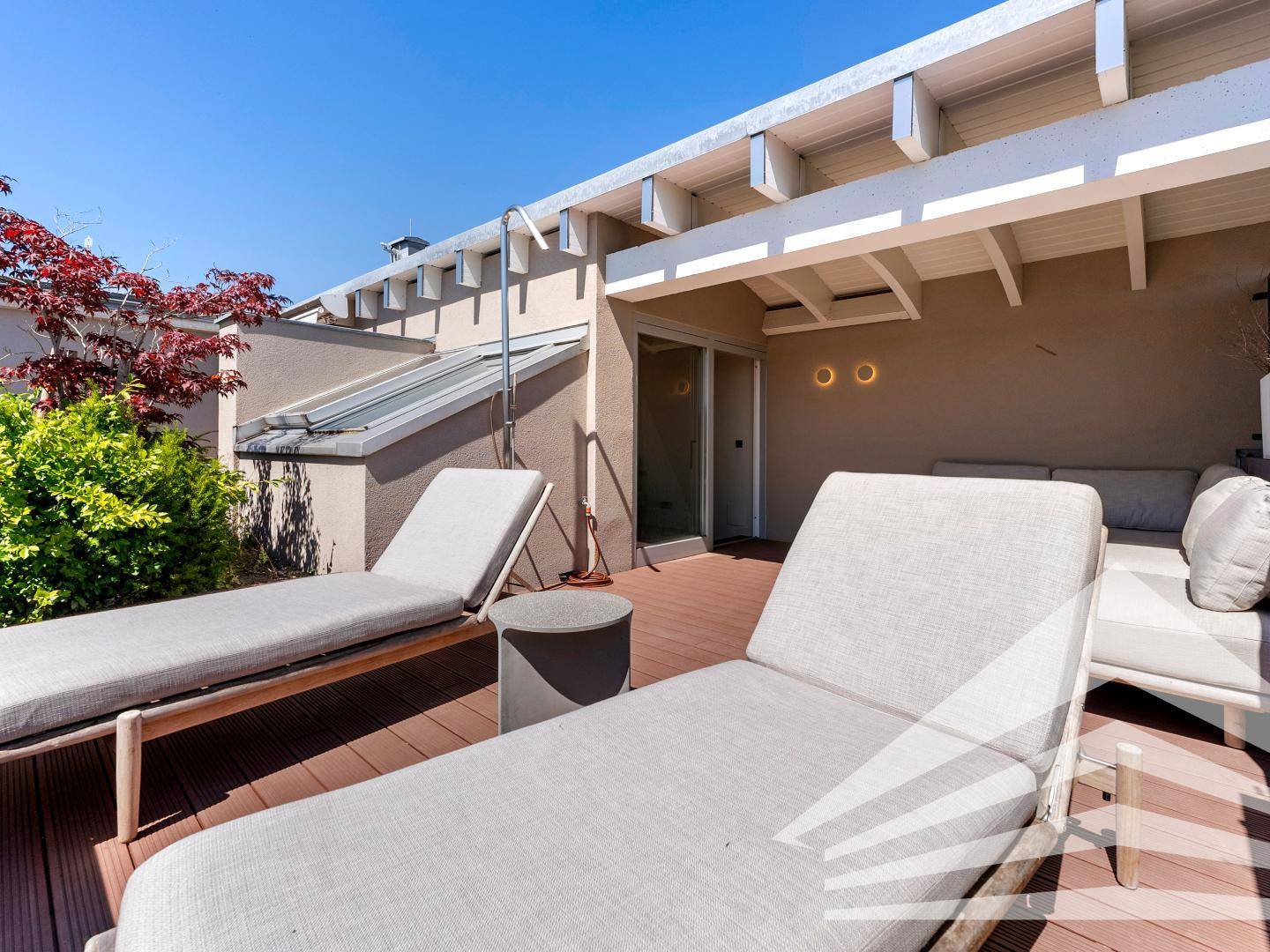 Weitläufige Dachterrasse mit Sonnenliegen, Pflanzen und Blick auf die Umgebung.