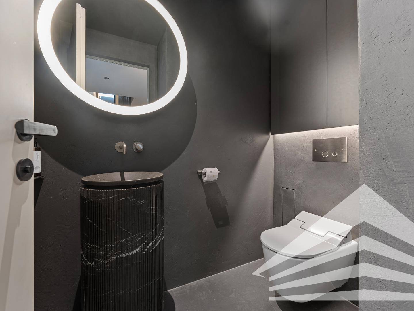 Modernes Gäste-WC in dunklen Farbtönen mit stilvollem Waschtisch und Wand-WC.