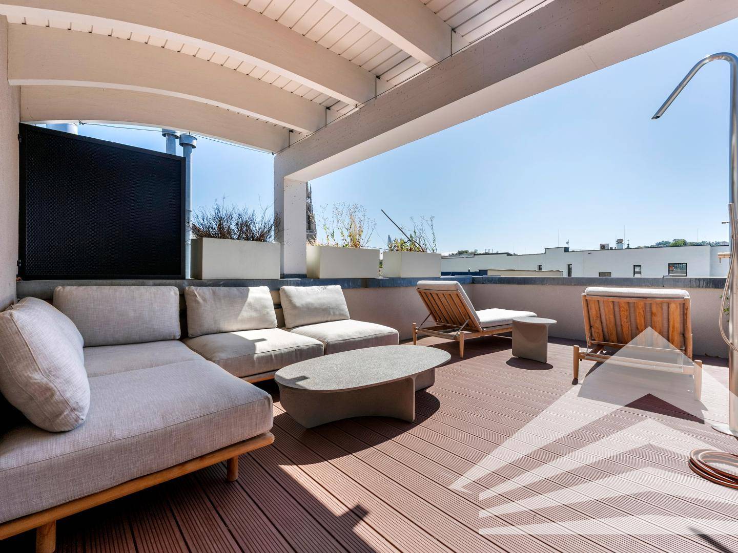 Große überdachte Dachterrasse mit Lounge-Möbeln und Sonnenliegen für Entspannung im Freien.