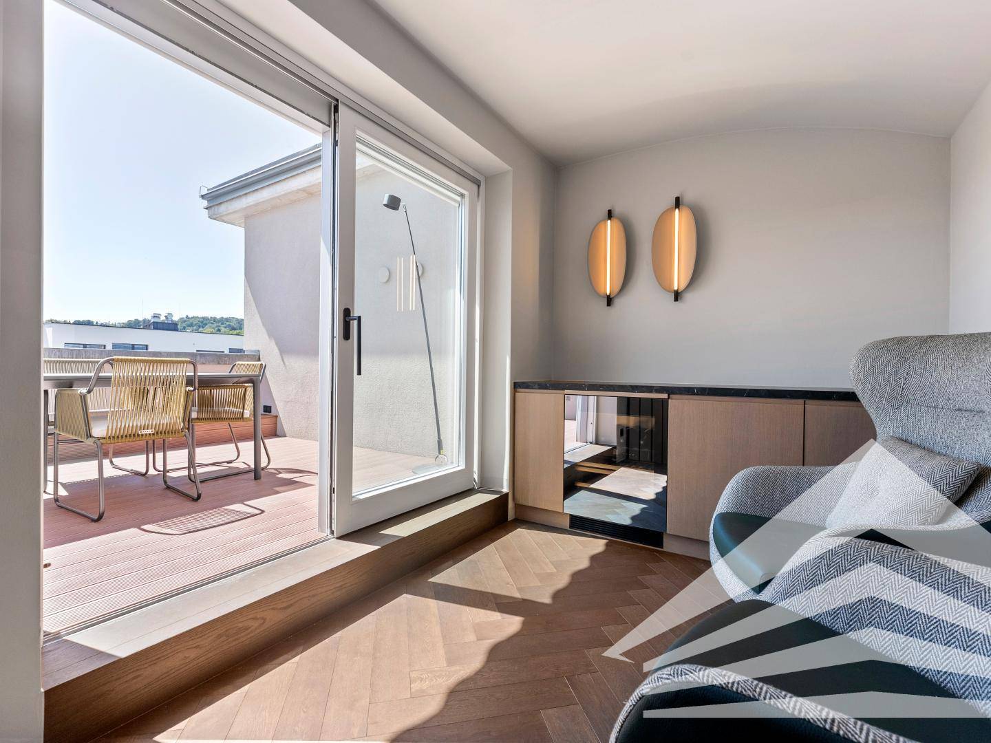 Heller Raum mit Zugang zur Dachterrasse, ausgestattet mit einem bequemen Sessel und Sideboard.