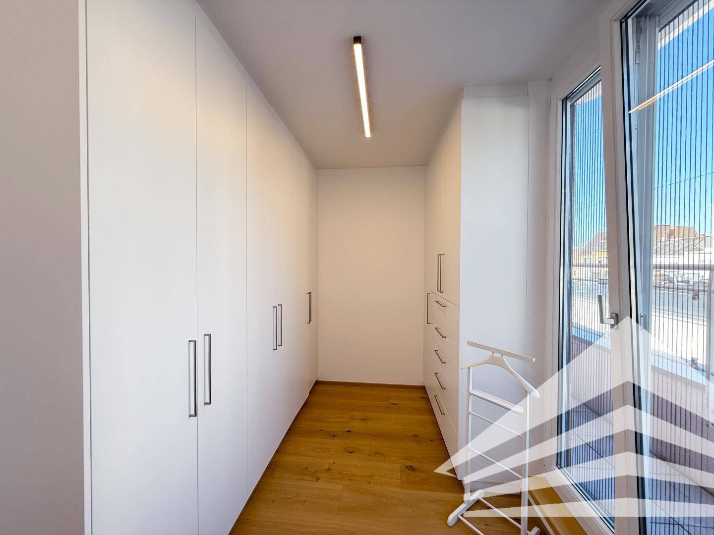 Praktischer begehbarer Kleiderschrank mit viel Stauraum und natürlichem Licht.