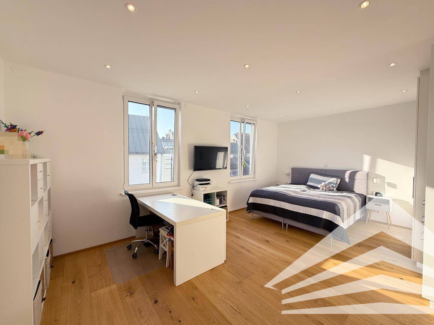 Geräumiges Schlafzimmer mit Holzboden, Schreibtisch und großen Fenstern für viel Licht.