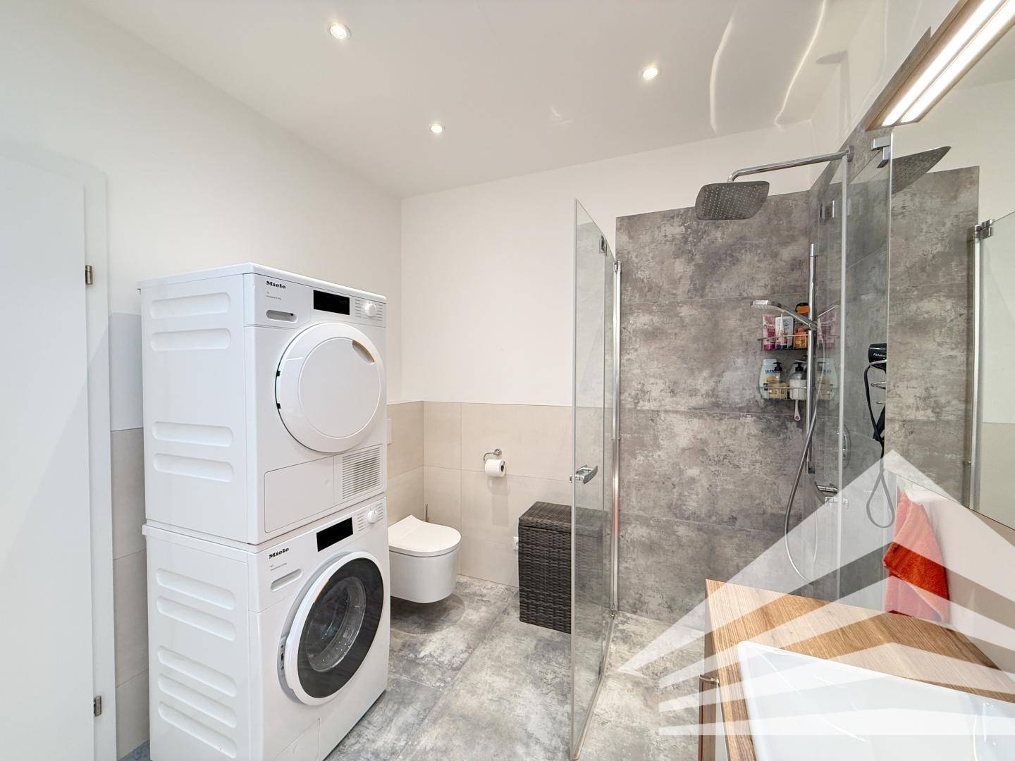 Geräumiges Badezimmer mit Dusche, Badewanne und integrierter Waschmaschine und Trockner.