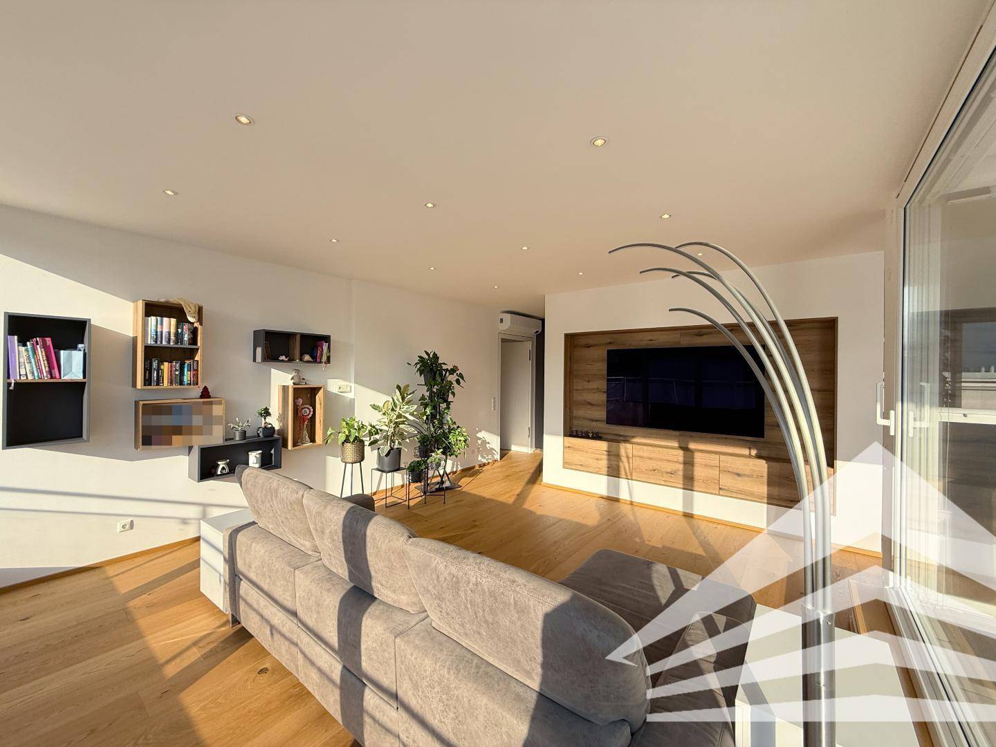 Geräumiges Wohnzimmer mit Holzboden, integriertem TV-Möbel und modernen Regalen.
