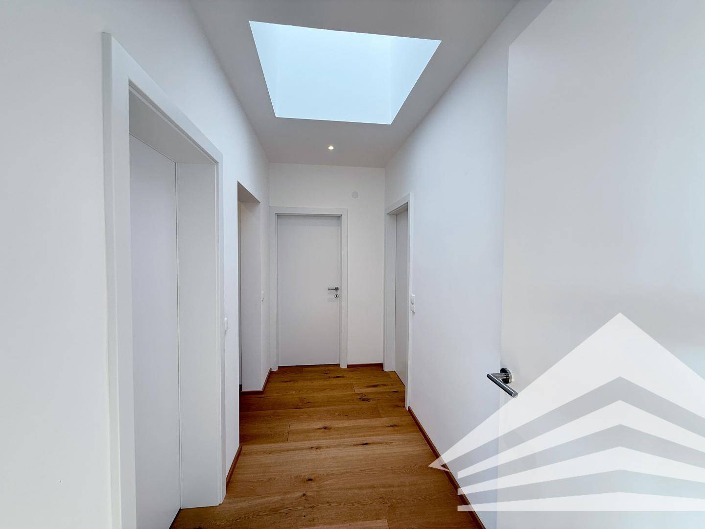 Heller Flur mit Holzboden und Oberlicht, das für natürliches Licht sorgt.