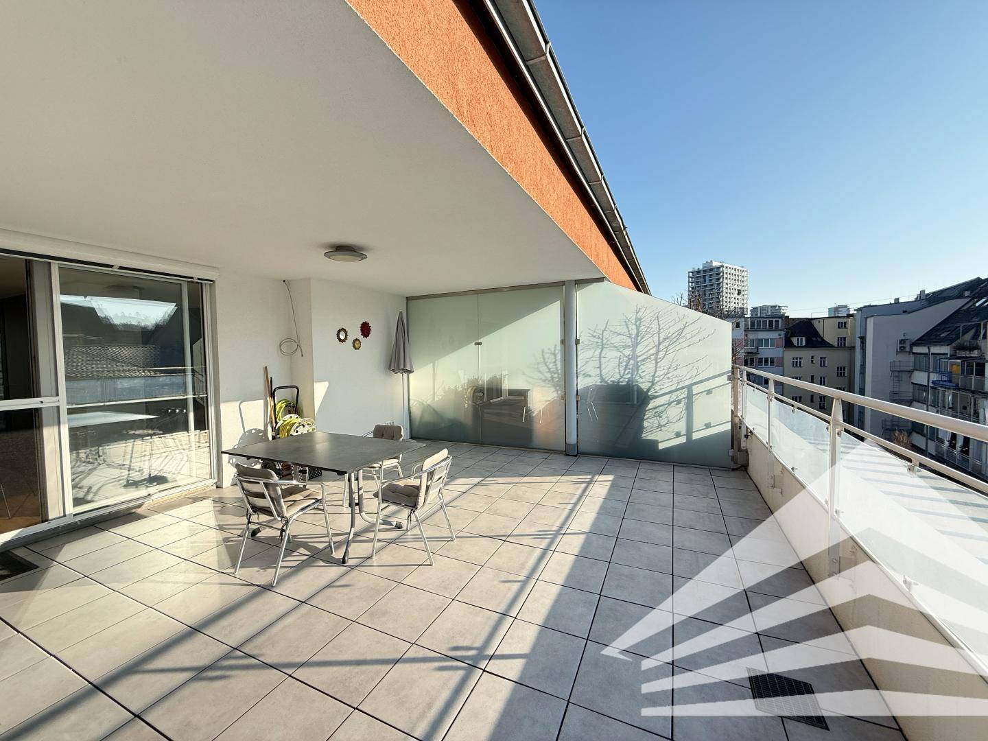 Geräumige Terrasse mit Fliesenboden und moderner Glasabtrennung, ideal für Entspannung im Freien.