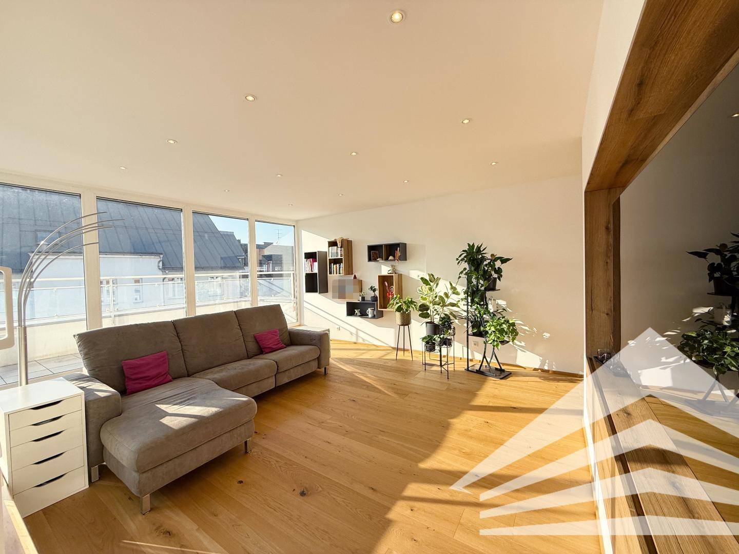 Helles Wohnzimmer mit beigem Sofa, Holzboden und Zugang zur sonnigen Terrasse.