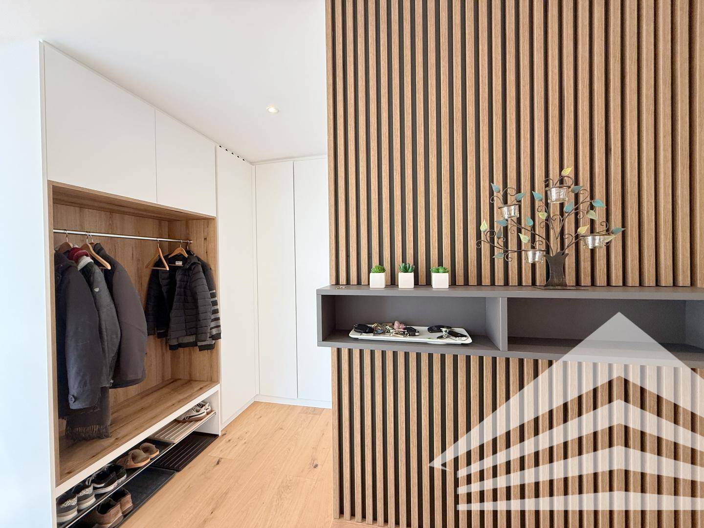 Moderner Eingangsbereich mit Holzlamellenwand, Garderobe und integrierten Schränken.