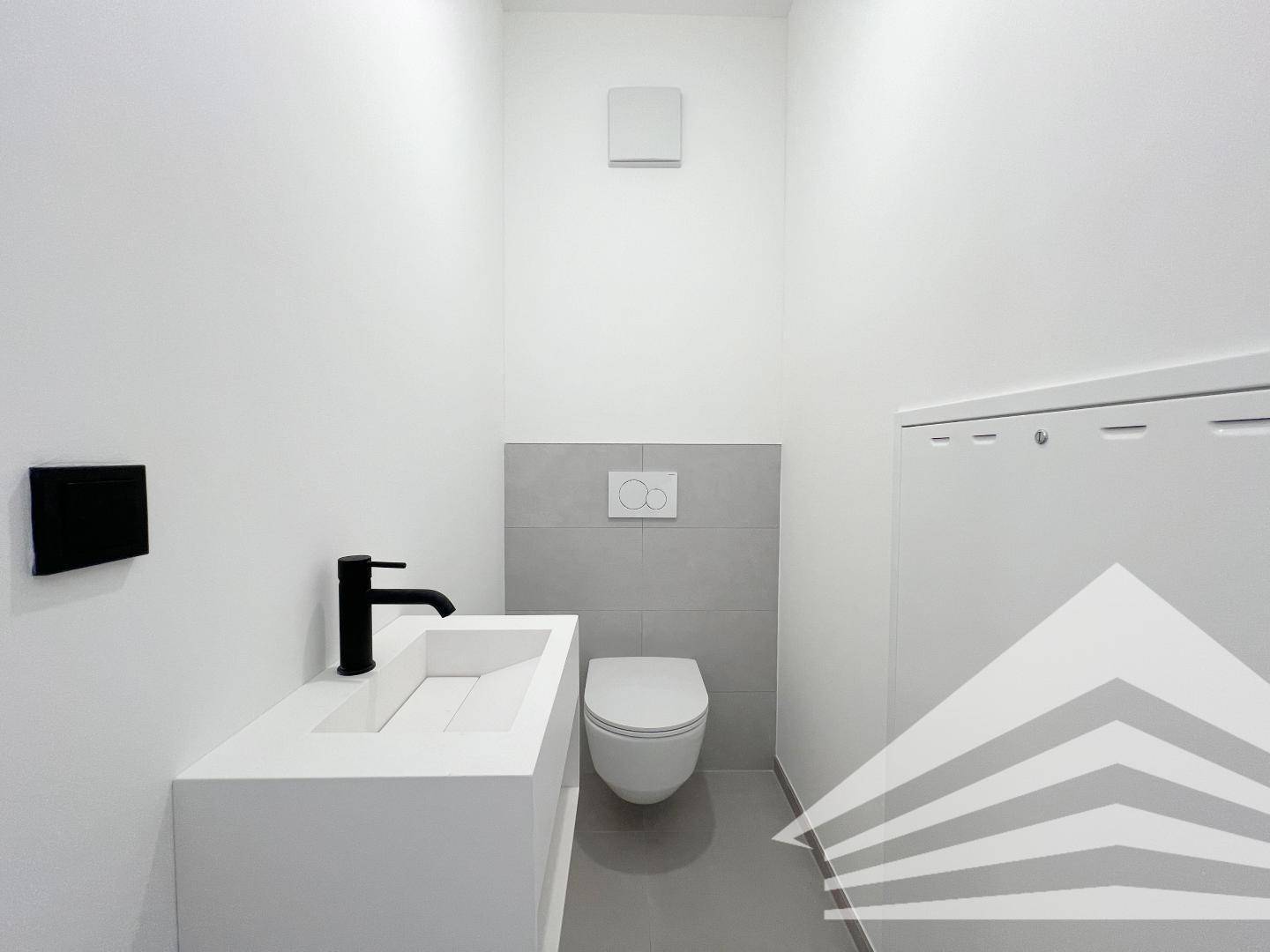 Modernes Gäste-WC mit wandhängender Toilette und stilvollem Waschbecken mit schwarzem Wasserhahn.