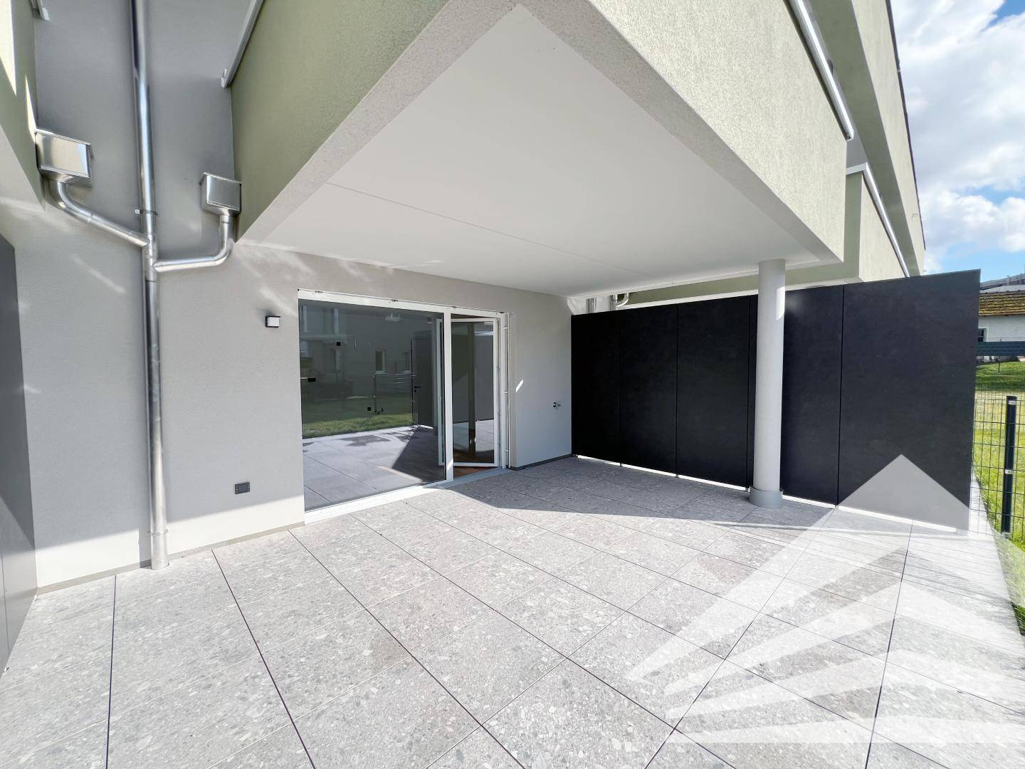 Geräumige überdachte Terrasse mit Zugang zum Innenbereich durch eine große Glasschiebetür.