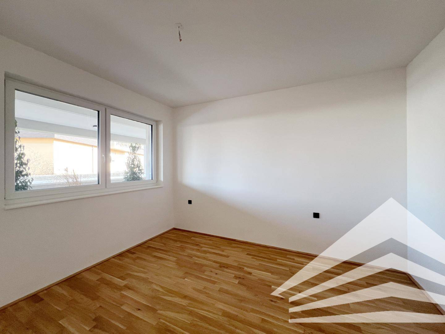 Helles Zimmer mit Holzboden und Fenster, ideal als Schlafzimmer oder Büro.