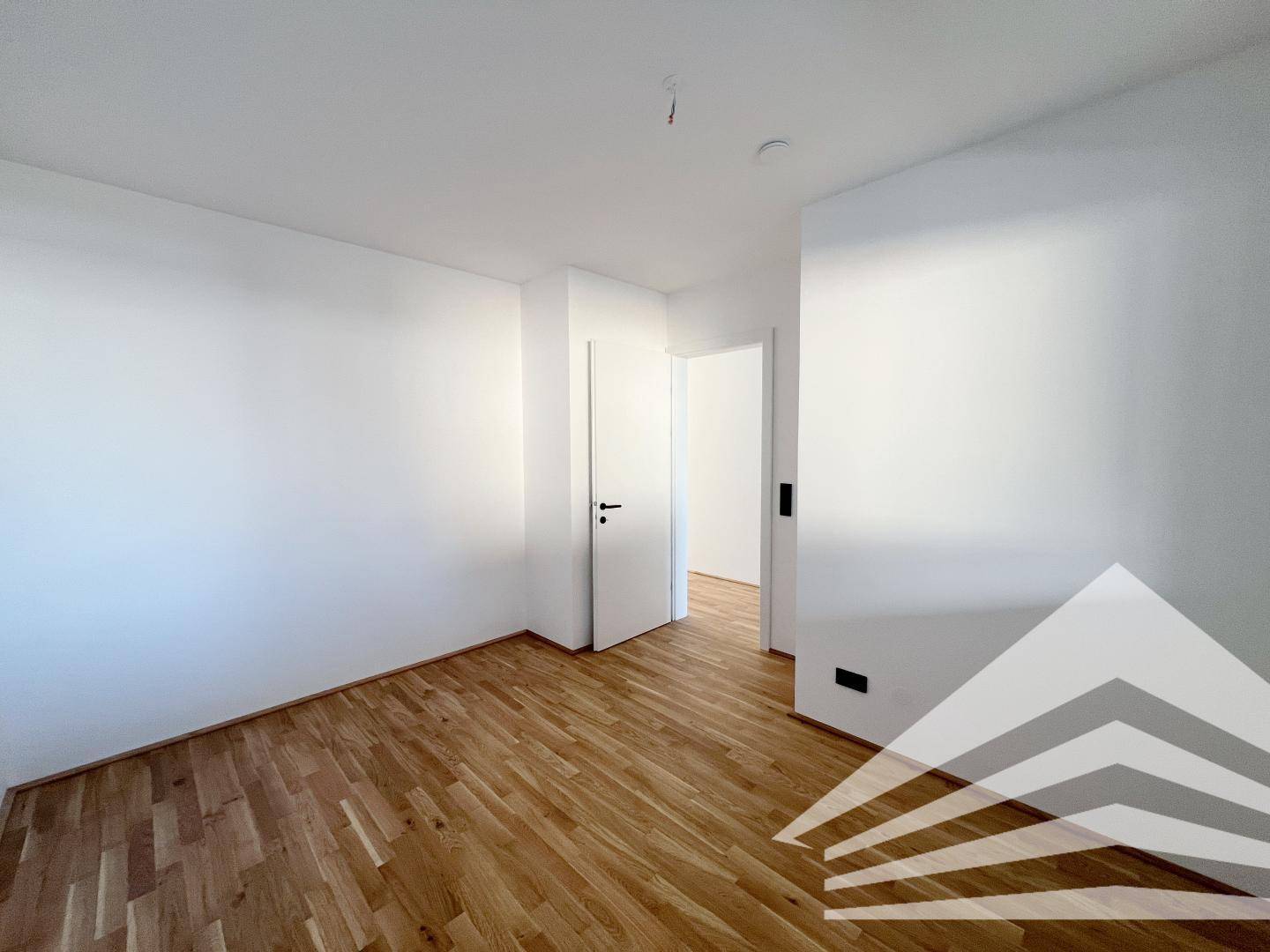 Unmöbliertes Zimmer mit Holzboden und weiß gestrichenen Wänden, bereit zum Einzug.