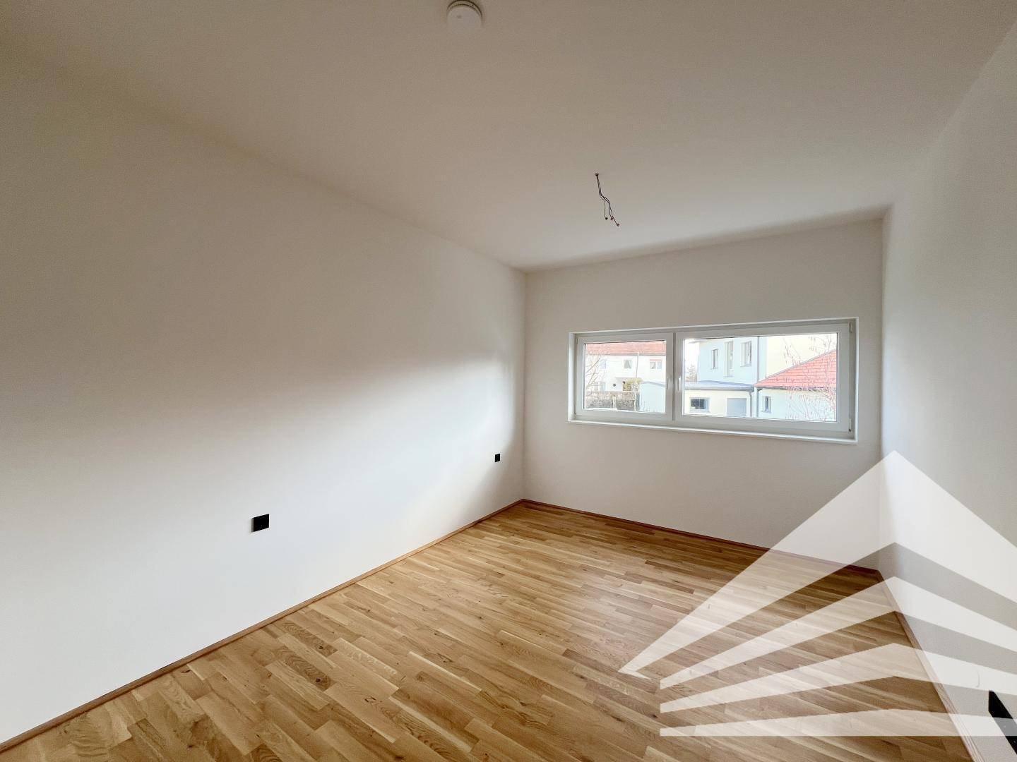 Helles Schlafzimmer mit Eichenparkettboden und weißen Wänden, bereit zur individuellen Gestaltung.