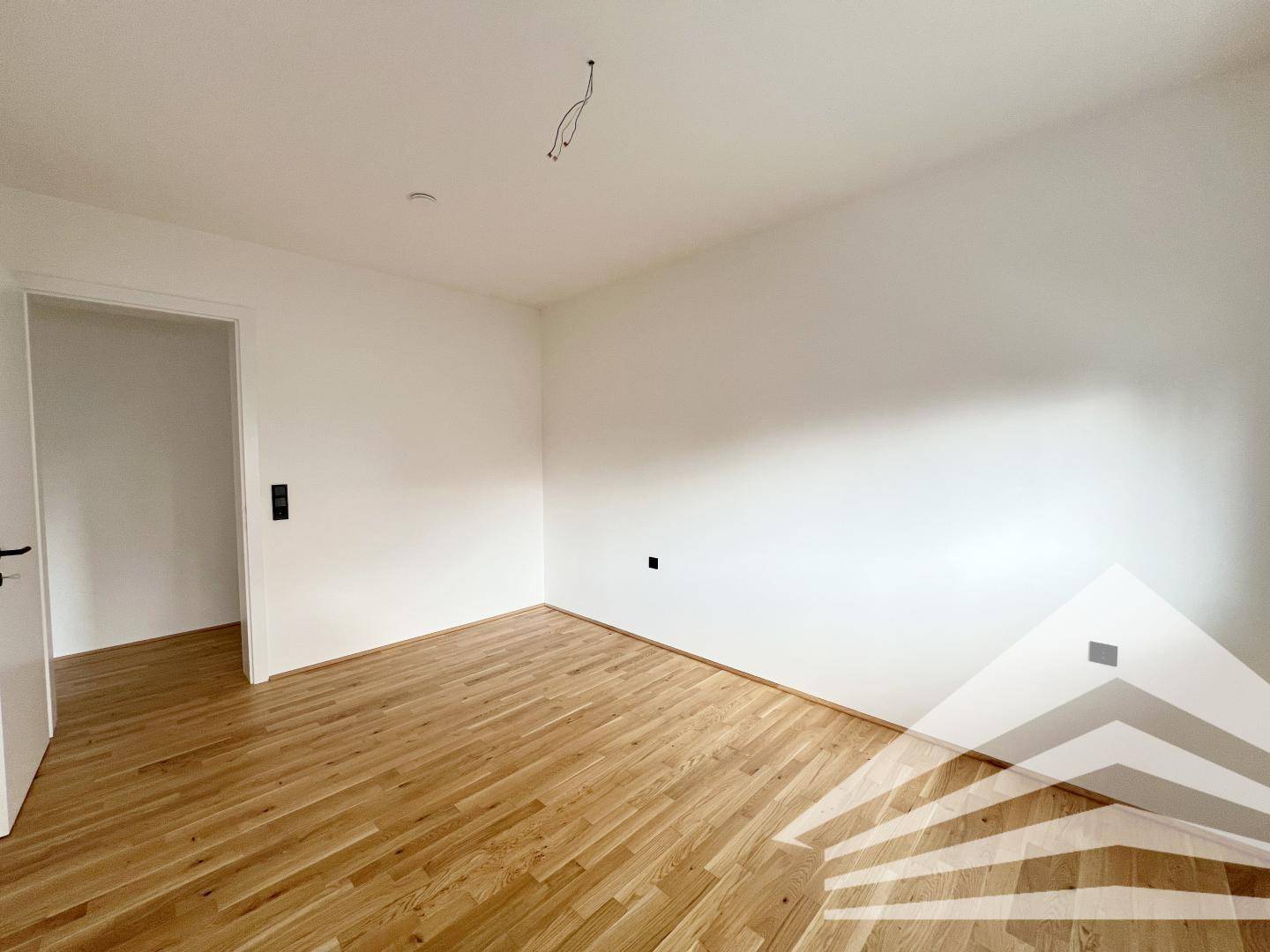 Geräumiges Schlafzimmer mit hellem Parkettboden und weißen Wänden, ideal für Ruhe und Erholung.