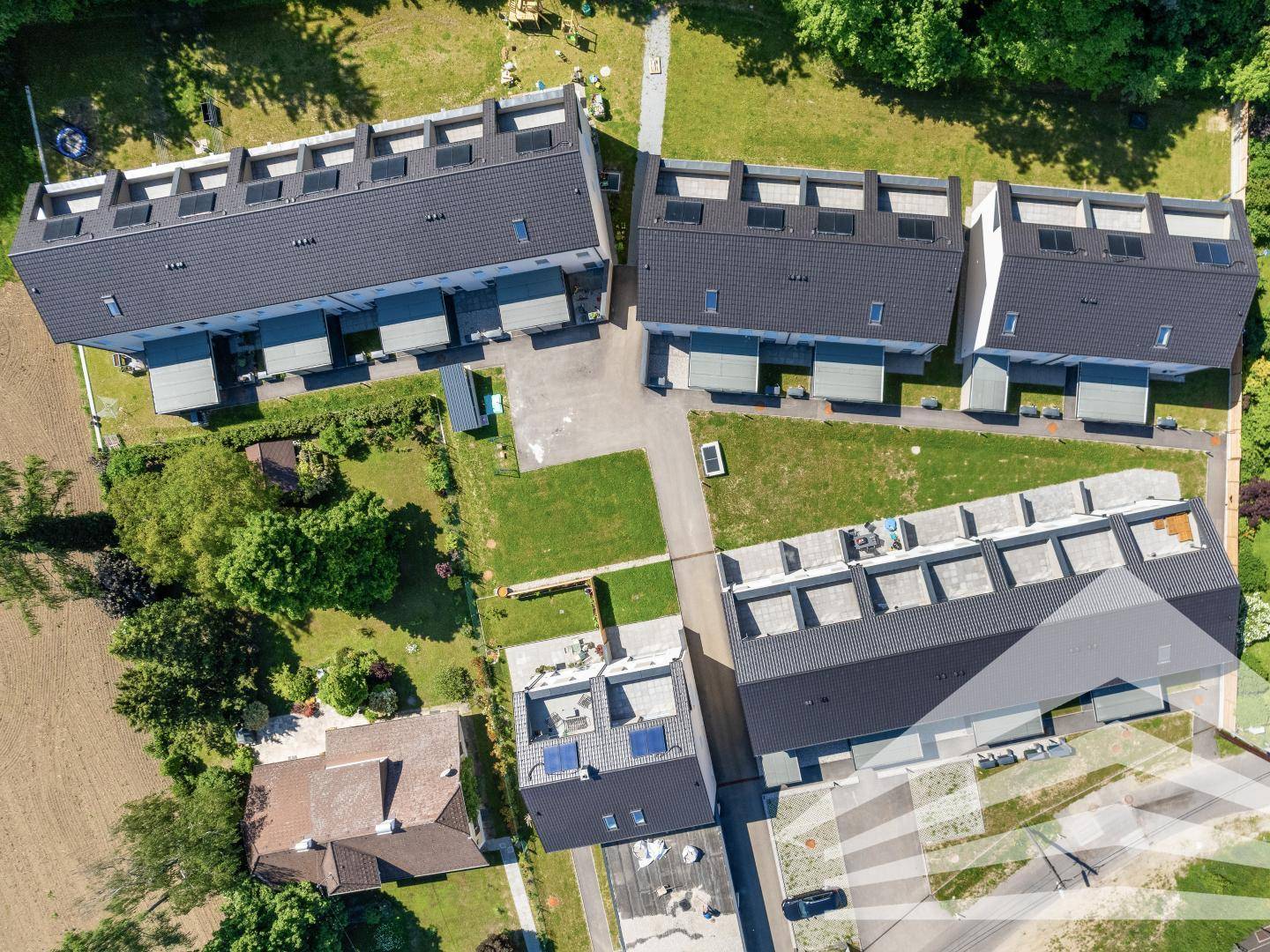 Luftaufnahme einer Siedlung mit modernen Reihenhäusern und Grünflächen.