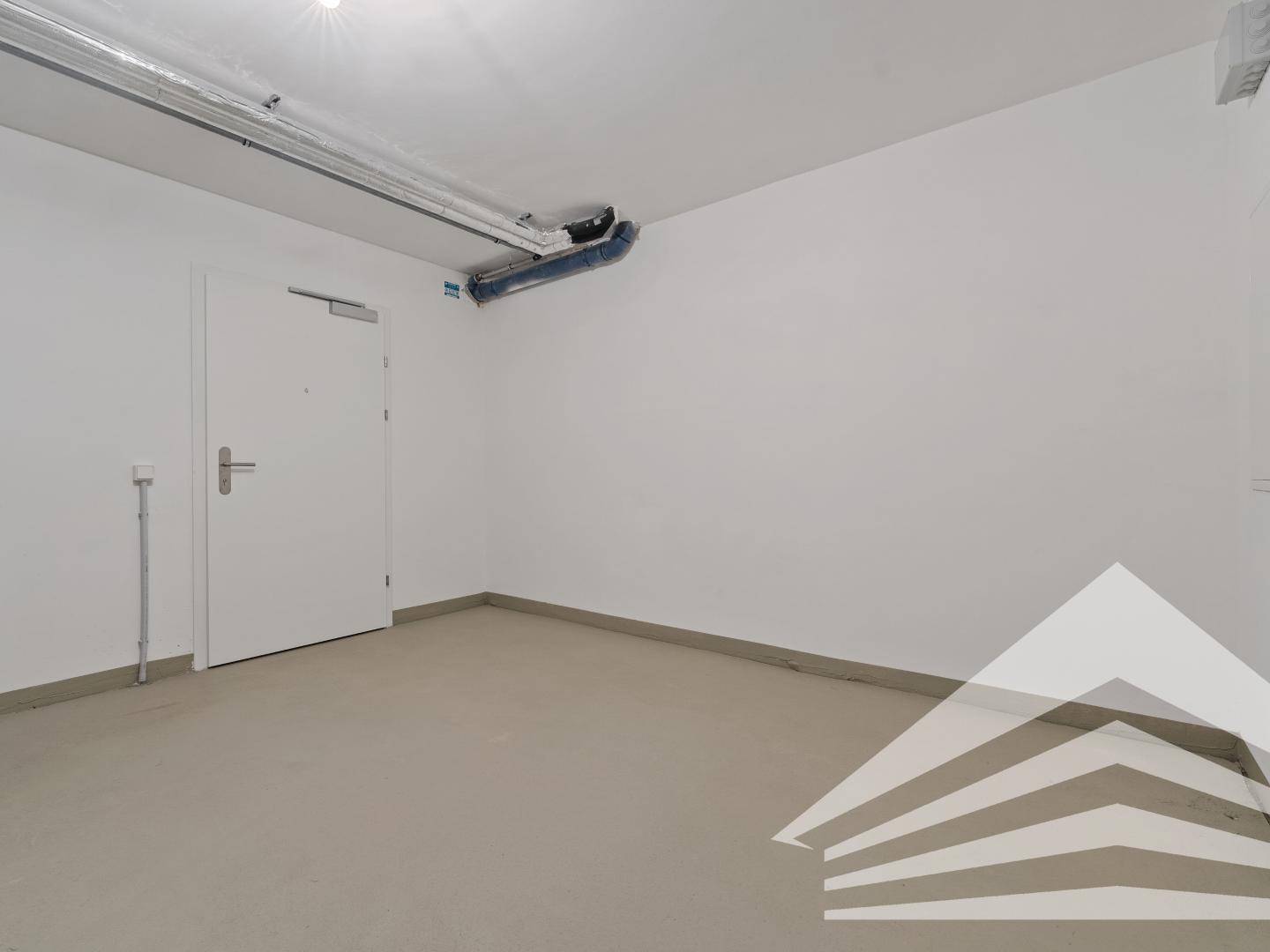 Geräumiger Hauswirtschaftsraum im Untergeschoss mit Betonboden und sichtbaren Leitungen.