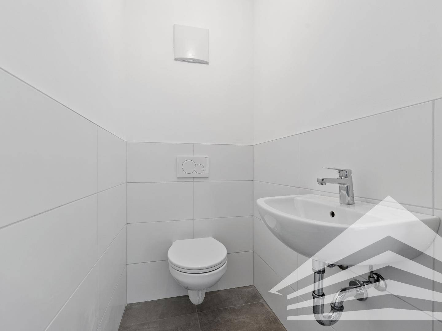 Modernes Gäste-WC mit wandhängender Toilette, kleinem Waschbecken und weißen Fliesen.